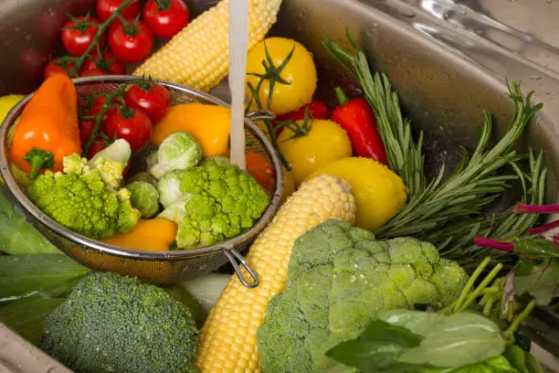 Photo of Colored vegetables in a metal shell. Water jet.