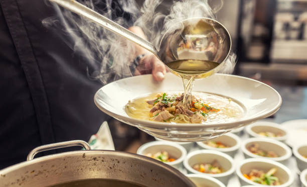 lo chef versa brodo in una zuppa di pollo con noodles, carne e verdure. - mestolo foto e immagini stock