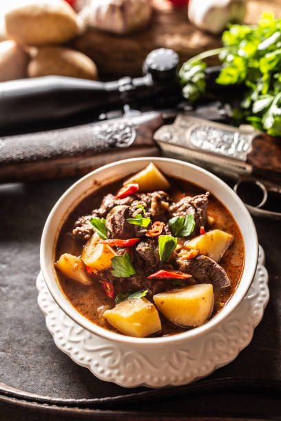 istock Deer stew in a bowl hunting weapon as a decoration. 1272863868