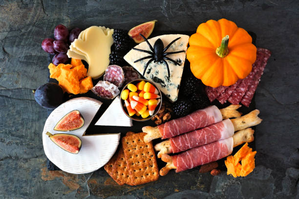 tabla de charcutería tema de halloween, vista de arriba hacia abajo contra un fondo oscuro - cheese antipasto cracker grape fotografías e imágenes de stock