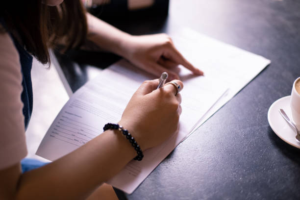 modèle de libération document de signature par les mains de femme sur la table de café dans l’heure du matin - laisser partir photos et images de collection