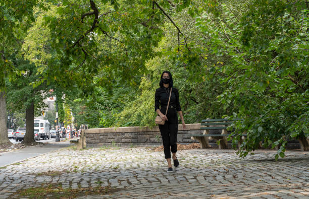 Teenage girl wearing protective mask walking nearby Central Park, Manhattan, during the COVID-19 pandemic. A 17-years-old teenage girl wearing protective mask in Central Park, Manhattan, NY black hair emo girl stock pictures, royalty-free photos & images
