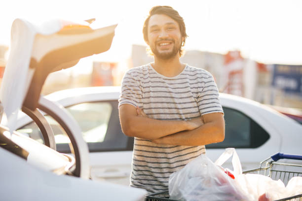 istock Man storing bucket with grocaries into a car trunk 1272878164