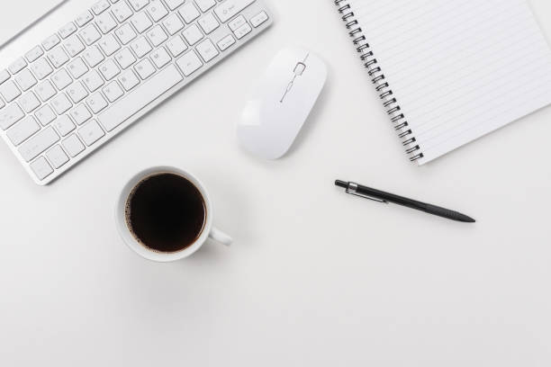 istock Workspace with computer keyboard, office supplies, and coffee cup on white background. Top view with copy space. 1272879092