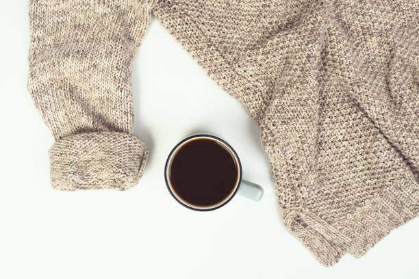 istock Women's fashion beige pullover and cup of coffee on a white background 1272886890