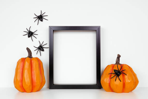 istock Mock up black frame with Halloween pumpkin decor on a shelf or desk against a white wall with spiders 1272887868