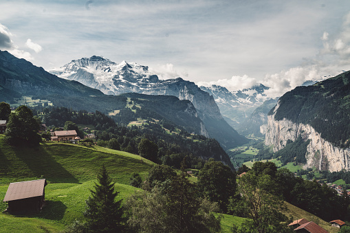The Lauterbrunnen Valley as seen from the town of Wengen, Switzerland. Waterfalls  falling over the stark rock cliffs. Snow capped mountains in the background.