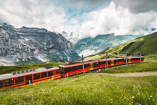 Famous railway from Wengen and Lauterbrunnen valley to Jungfraujoch. Red modern mountain train driving trough Swiss Alps.