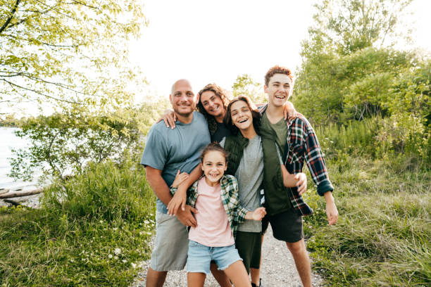 famiglia che lega e si diverte insieme al lago. tre bambini e genitori che abbracciano e sorridono alla telecamera. - fourty five foto e immagini stock