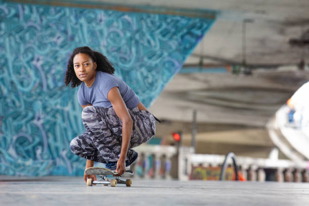 istock Young sportive woman concentrated as she rolls forward crouching on her skateboard 1272892139