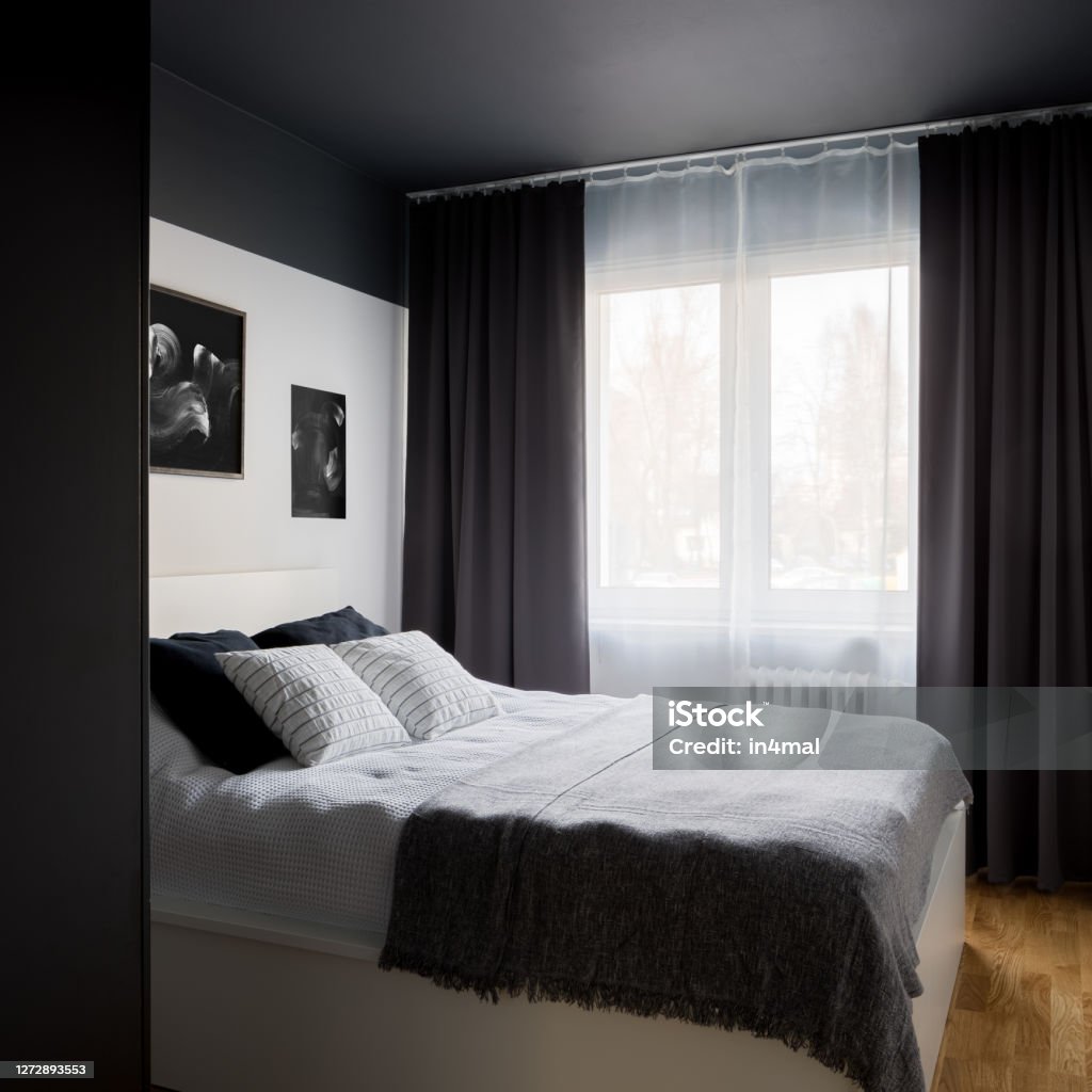 Small bedroom with black ceiling Small and stylish designed bedroom with modern black ceiling and white double bed Dark Stock Photo