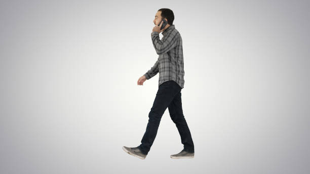 istock Young bearded man walking and talking on the mobile phone on gra 1272897209