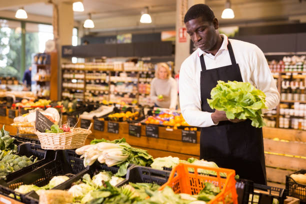 istock Salesman putting vegetables on store showcase 1272897860