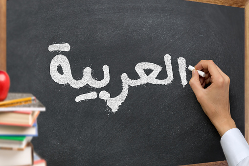Hand writing on a blackboard in a Arabic language learning class course with the text \
