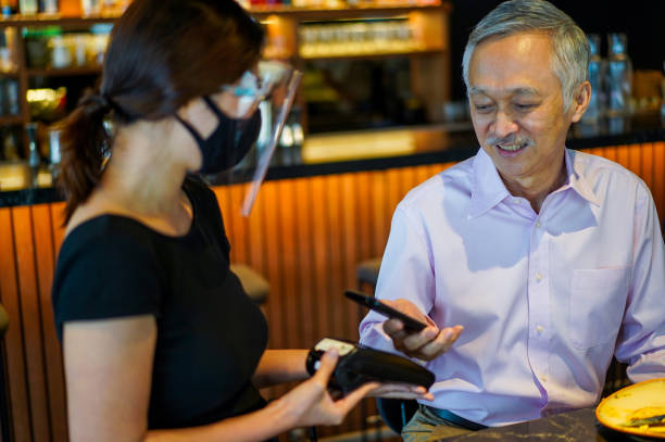 istock Senior Asian man making a contactless payment in a restaurant. 1272904680