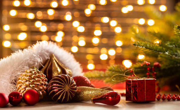 istock Xmas banner: santa hat with christmas decorations: cone, balls, tape, beads, gift box and Christmas tree on garland bokeh background. Copyspace. New year congratulations card 1272904744