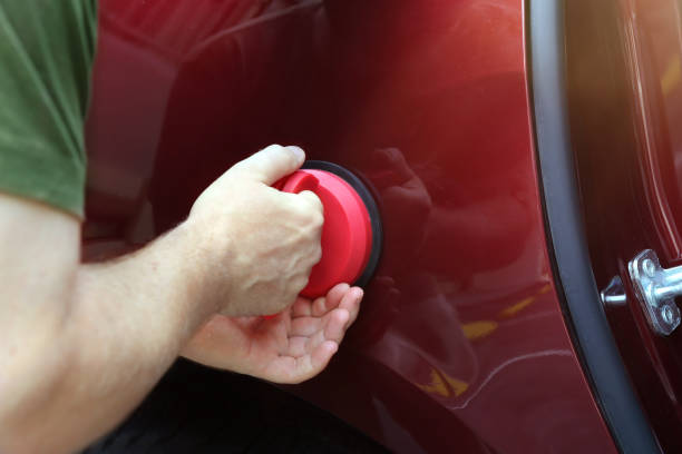 hombre arreglando la abolladura del coche por sí mismo - abollado coche fotografías e imágenes de stock