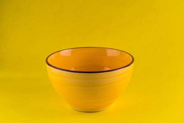 istock Yellow ceramic bowl on a yellow background. Close-up. 1272909497