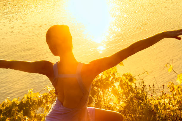 Beautiful female ballet dancer in purple skirt dancing in the intense warm light of sunset on the shores of West Hartford Reservoir in West Hartford, Connecticut.