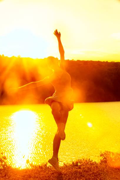 istock Woman dancing with intense reflections of the setting sun. 1272916152
