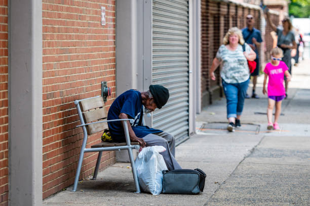 um velho sem-teto africano está sentado em um banco perto de uma parede de tijolos vermelhos - philadelphia pennsylvania sidewalk street - fotografias e filmes do acervo