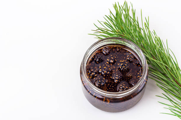 istock Unusual jam from pine cones in glass jar on white background among pine branches and cones. Organic and vegetarian sweet dessert close up, copy space for text. Remedy for colds 1272918146