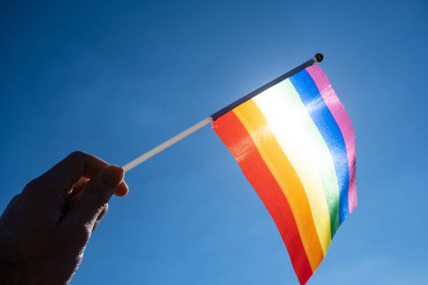 istock LGBT flag in a man's hand against a blue sky background 1272919846