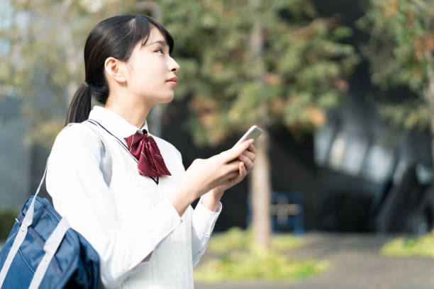 スマートフォンを使用してアジアの女子高生。 - 女子高生 ストックフォトと画像