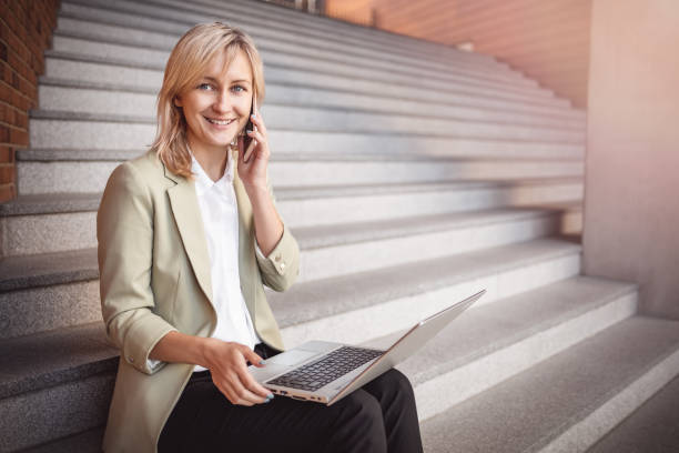 giovane donna felice con laptop e smartphone seduti sulle scale - private secretary foto e immagini stock