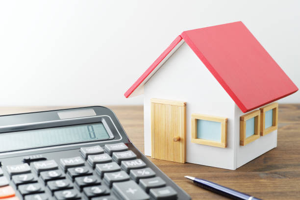 istock Miniature house and calculator on wood table. 1272926093