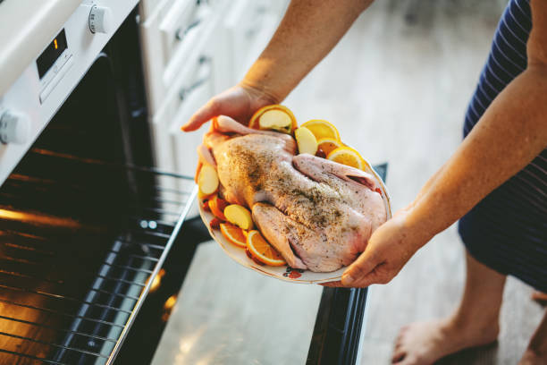 istock Woman puting raw duck with vegetables in oven 1272928273