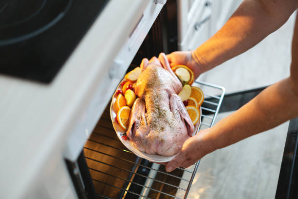istock Woman puting raw duck with vegetables in oven 1272928306