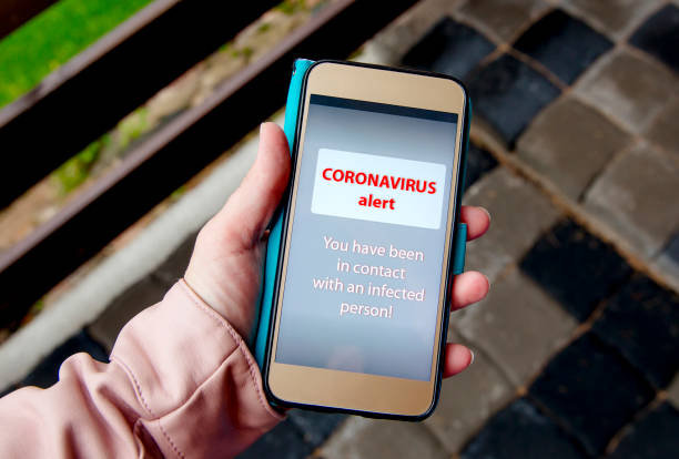 istock Modern Coronavirus warning system app concept. Person viewing smartphone screen and seeing Coronavirus warning sign. Lifestyle. 1272928624