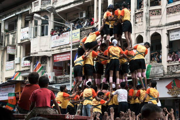 dos niños pequeños están viendo al grupo de jóvenes haciendo la pirámide humana en el día del festival janmashtami. - editorial indian culture traditional culture horizontal fotografías e imágenes de stock
