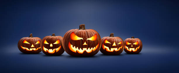 istock Five halloween, Jack O Lanterns, with evil spooky eyes and faces isolated against a blue lit background. 1272937132