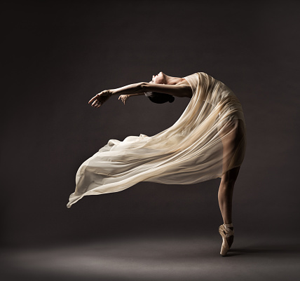 Bailarina bailando con tela de seda, bailarina de ballet moderno en tela ondulada, zapatos de Pointe, fondo gris photo
