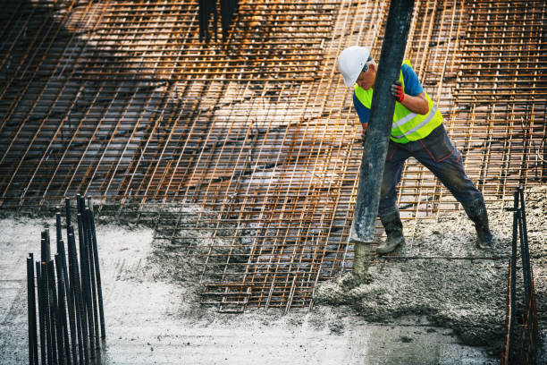 Pumping concrete over rebar mesh. Closeup of a construction worker guiding a hose from a concrete pump and filling rebar mesh. This is fast setting concrete, takes three hours to dry. reinforced concrete stock pictures, royalty-free photos & images