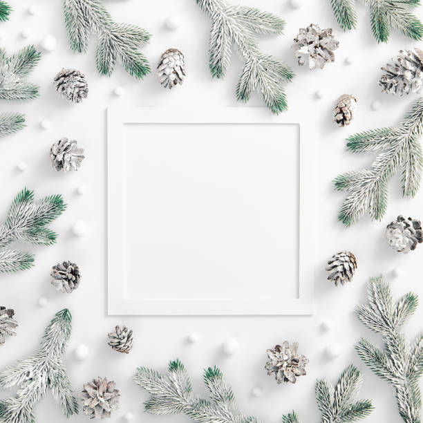 istock Evergreen tree branch with snow and pine cones. Square composition, flat lay, top view. Snow forest creative minimal layout. White paper frame template 1272943574