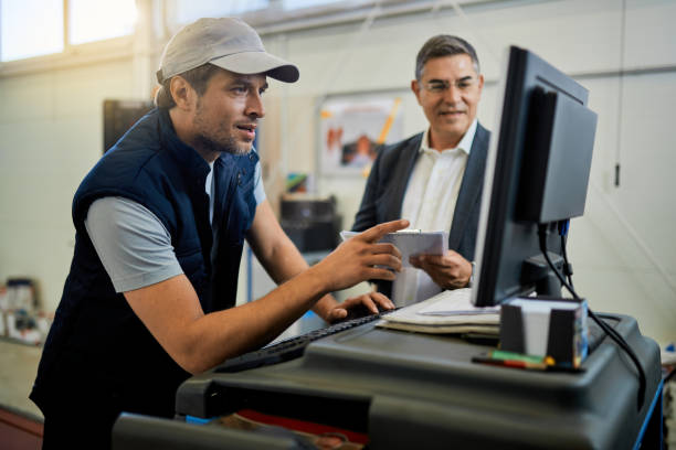 istock Car mechanic and his manager using computer in auto repair shop. 1272944082