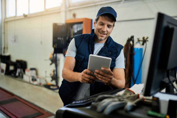 istock Happy auto repairman working on touchpad in a workshop. 1272945210