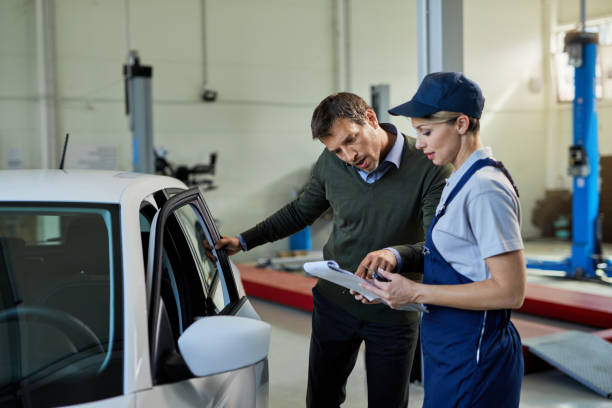 istock Auto repairwoman and her customer going through paperwork in a workshop. 1272945860