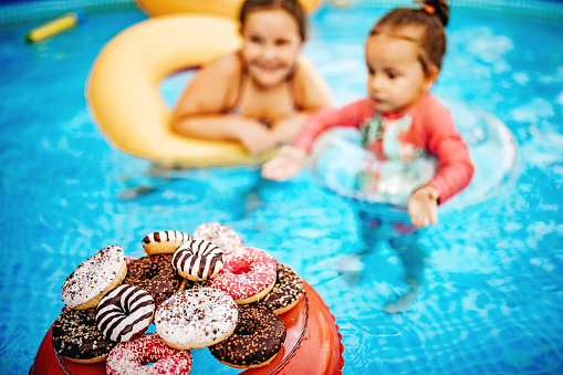 Girls drinking juice and eating doughnuts in swimming pool
