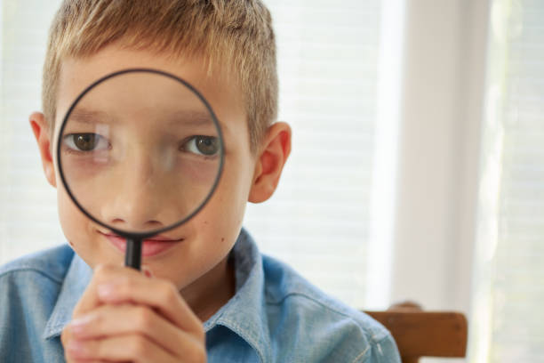 istock Teenage boy looking at camera through magnifying glass 1272947536
