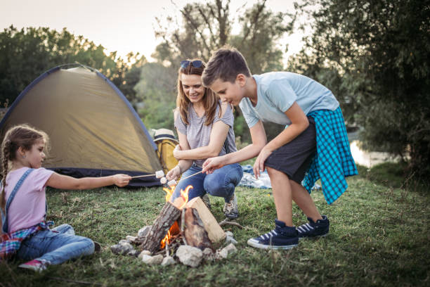 istock Mother and  children roasting marshmallows in campfire 1272949328