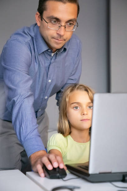 istock Middle-aged teacher checking task and standing behind girl 1272951136