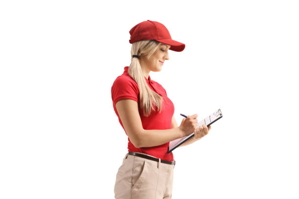 istock Woman delivery worker in a uniform writing on a clipboard 1272952427