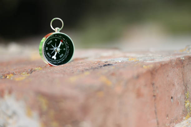 istock Iron compass on brick wall as symbol of tourism with compass 1272954158
