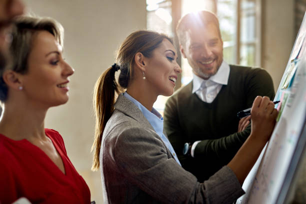 istock Happy businesswoman writing ideas on adhesive notes on whiteboard. 1272955181
