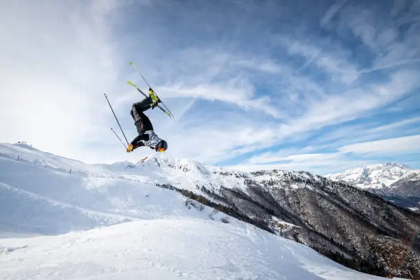 Skier doing a backflip jump in Alps ski resort, Alpe di Mera, Piedmont, Italy