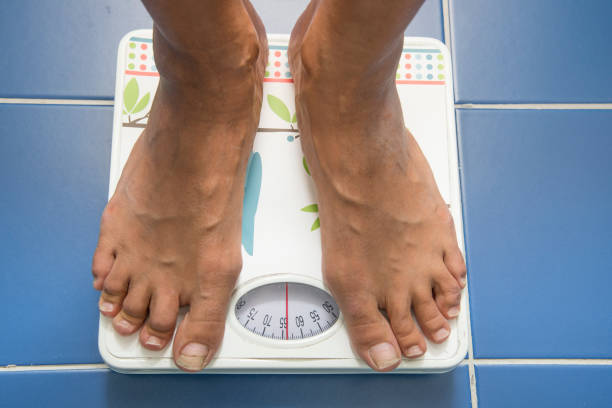 istock woman on a scale weighing herself 1272958621